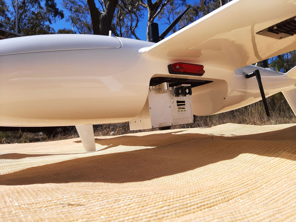 Fixed-wing drone with mounted LiDAR and photogrammetry sensors on launch mat in field environment